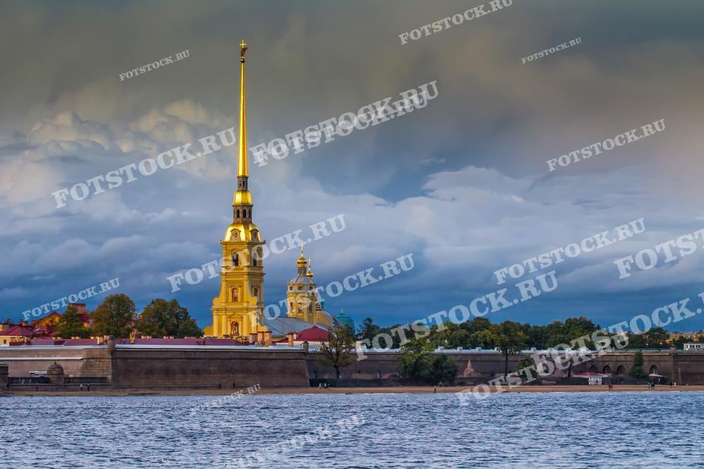 На фотографии изображена река Нева и Петропавловская крепость под серым небом. Данное изображение может выступать визитной карточкой Санкт-Петербурга.